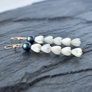 Long statement earrings by Yay Hawaii with five mother of pearl Pikake and black freshwater pearls, featuring intricate floral design.