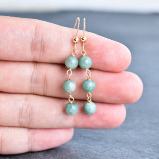 Triple linked 6mm jade dangle earrings featuring vibrant green jade beads with gold-tone findings.