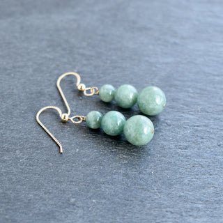 Graduated jade bead cluster earrings with gold hooks, featuring varying green jade beads and a stylish, elegant design.