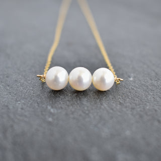Yay Hawaii triple 8mm white pearl necklace with smooth, round pearls on a delicate silver chain, close-up view.