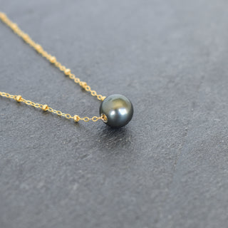 Round Tahitian pearl pendant on satellite chain necklace by Yay Hawaii, showcasing a lustrous black pearl and delicate chain detail.