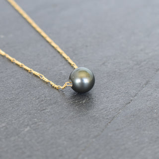 Round Tahitian pearl pendant on a gold Figaro chain, jewelry piece from Yay Hawaii displaying elegant pearl and chain design.