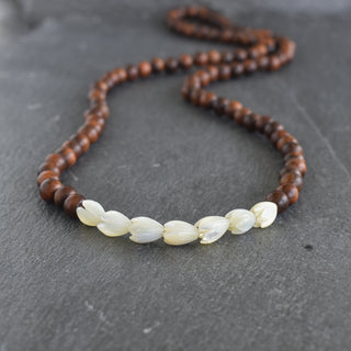Pikake and rosewood necklace by Yay Hawaii featuring floral beads and natural wooden accents, laid out on a neutral background.