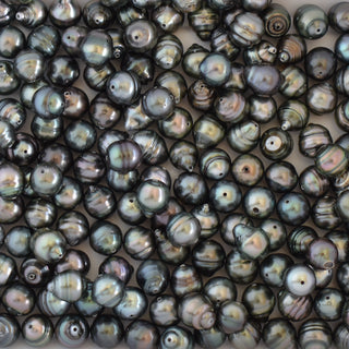 Loose Tahitian pearls from Yay Hawaii, drilled for jewelry making, showcasing their dark, lustrous surface and natural shape.