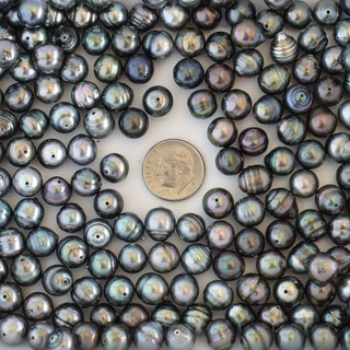 Loose Tahitian pearls from Yay Hawaii, drilled and round, showcasing their dark iridescent luster on a neutral background.