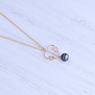 Monstera leaf pendant and black pearl necklace with silver or gold chain, stylish jewelry piece on a neutral background.